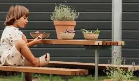 Garten Kindermöbel Basic Kinder-Picknicktisch aus Holz mit zwei Bänken, Kind sitzt daran im Garten
