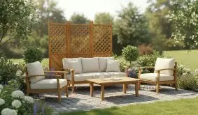 Holz-Sichtschutz mit Rankgitter steht hinter einer Gartenlounge aus hellen Polstermöbeln auf einer gepflasterten Terrasse, umgeben von Pflanzen.