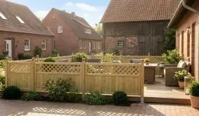 Gartenzaun aus Holz mit Rankgitter als Sichtschutz rund um gemütliche Terrasse mit Sitzgruppe.