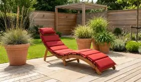 Klappliege Pablo aus Holz mit roter Polsterauflage, geschwungene Gartenliege auf Terrasse im Garten.