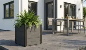 Kunststoff Blumenkübel auf einer Terrasse mit Haus und Gartenmöbeln im Hintergrund