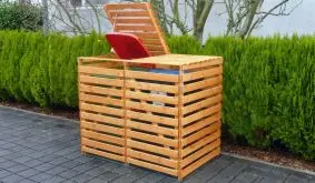 Unsere Mülltonnenverkleidung "Kemi" aus massivem Kiefernholz. In der Farbe: Honigbraun