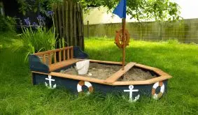 Sandkiste Boot aus Holz in Anthrazit und Braun mit Sitzbank, im Garten auf Rasen