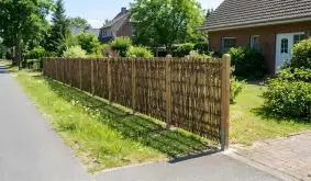 Sichtschutz Haselnuss mit senkrecht geflochtenen Ruten an Holzpfosten, entlang Gehweg