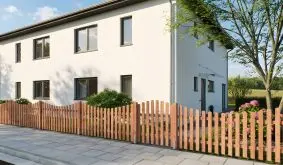 Lattenzaun aus Douglasienholz mit geschwungenem Verlauf an Grundstücksgrenze vor Wohnhaus mit weißer Putzfassade.