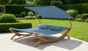 Gartenbett mit Dach Marbella mit blauem Stoffdach und Holzgestell auf einer Terrasse im Garten