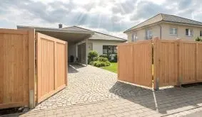 Holzzaun Douglasie Massiv, geschlossene Holzfelder mit Rahmen und Beschlägen, Doppeltor im Einfahrtsbereich.