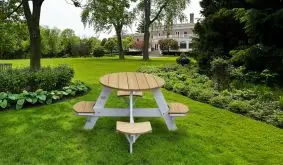 Garten Kindergarnitur mit rundem Holztisch und hellen Sitzbänken auf grünem Rasen im Garten