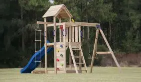 Kinderspielturm Leo aus Holz mit Holzdach, blauer Rutsche und Kletterwand mit bunten Griffen im Garten