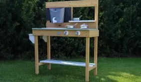 Matschküche aus Hemlock-Holz mit Wasserhahn, Arbeitsplatte und Ablagefach, aufgebaut auf Rasen im Garten