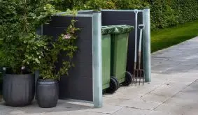 Schiefergraue Mülltonnenverkleidung aus wetterfestem WPC. Erhältlich in zwei Größen (Länge: 196 oder 302 cm) für zwei oder drei 240-Liter-Behälter