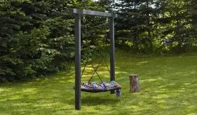 Outdoorschaukel mit dunklem Rahmen und runder Nestschaukel, aufgehängt an Seilen, auf Rasen