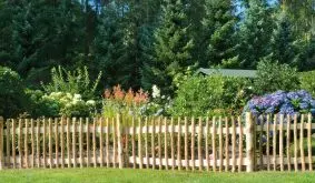 Staketenzaun aus naturbelassenem Haselholz. Die Latten sind mit 6 cm Abstand auf zwei Querriegeln befestigt