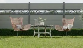 Moderner Garten mit zwei Loungesesseln und Tisch vor grauem Steckzaun mit dekorativem Steckzaun Designeinsatz.