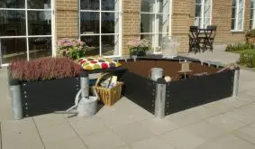 Hier sehen Sie das Pipe Hochbeet WPC Set mit dem 138 x 138 x 72 cm und dem 78 x 138 x 36 cm Modul, verbunden durch das 60 cm Sitzbrett