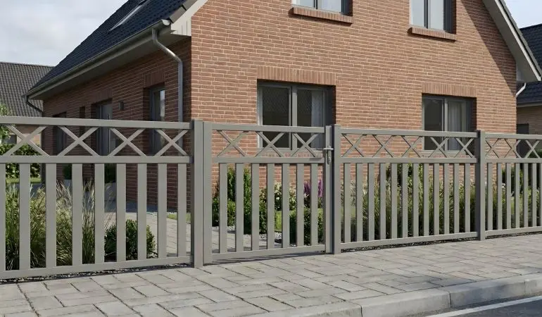 Grauer Aluminium-Rahmenzaun mit integrierter Tür vor Einfamilienhaus mit gepflegtem Vorgarten