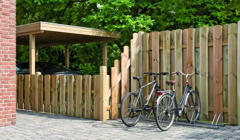 Sichtschutzzaun Frankfurt aus Holz mit senkrechten abgerundeten Latten, Zaun mit Schrägelement entlang des Weges zwischen Haus und Carport.
