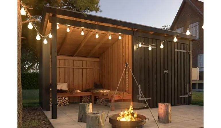 Der Gartenunterstand XL – eine clevere Gebäudekombination aus Gartenhaus, Lagerfeuerhütte und Geräteschuppen.
Das Bild zeigt ein mit Holzfarbe (Plus Color Anthrazit) gestrichenes Gebäude. Der Bausatz ist unbehandelt