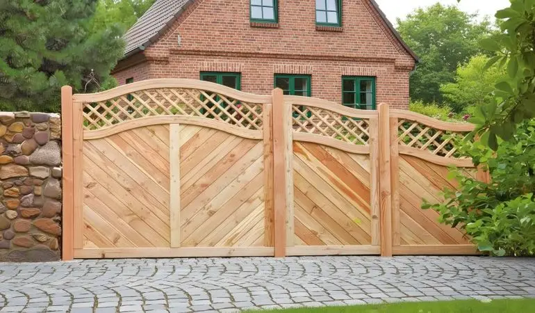 Dekorativer Holzzaun mit Gittermuster im Garten, geschwungene Form, umgeben von grünen Bodendecker-Pflanzen und Steinmauer.