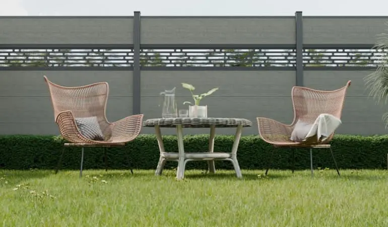 Moderner Garten mit zwei Loungesesseln und Tisch vor grauem Steckzaun mit dekorativem Steckzaun Designeinsatz.