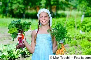 Junges Mädchen mit je einem Bund Möhren und Rote Beten in der Hand