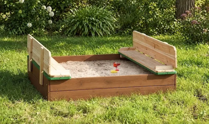 Sandkasten mit Sitzbänken und Lehnen Holzsandkasten mit zwei Sitzbänken und Rückenlehnen auf einer Rasenfläche