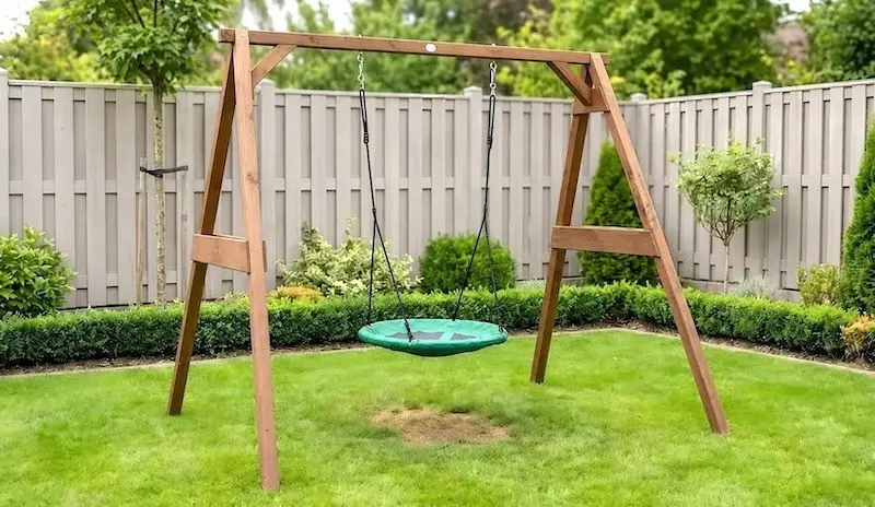 Einzelschaukel mit Nestschaukel Holzgestell mit grüner Nestschaukel auf einer Rasenfläche im Garten
