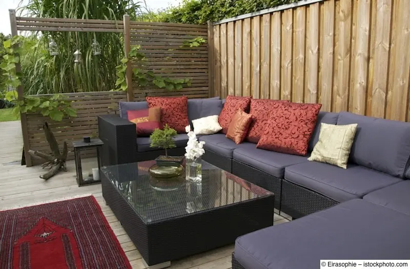 Von Sichtschutzwänden aus Holz eingerahmte Terrasse mit Lounge-Garnitur