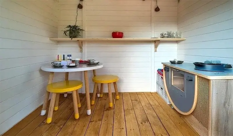 Blick ins Innere eines Kinderspielhauses Blick ins Innere eines Kinderspielhauses aus Holz mit Kinderküche und Garnitur