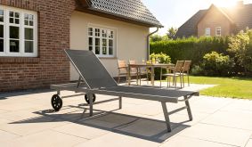 Garten Sonnenliege Macon mit silbernem Aluminiumgestell, schwarzem Textilene und Rädern auf einer Terrasse