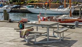 Outdoor Sitzgruppe Twist mit grauen Planken und verzinktem Stahlgestell auf Holzsteg am Wasser